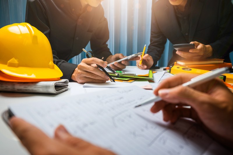 Managers reviewing plans and schedules together at a table with a hard hat